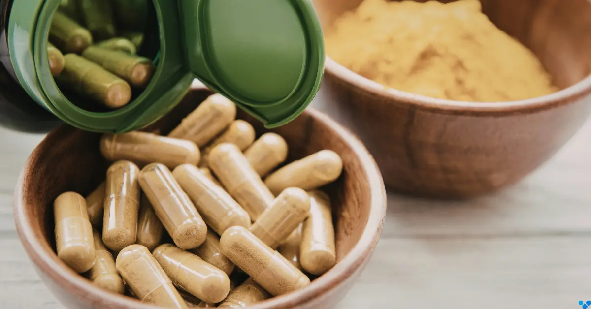 Natuerliche Nahrungsergaenzungsmittel Kapseln in einer Holzschale neben pflanzlichem Pulver als Tabletten fuer Sexlust beim Mann